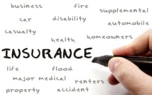 Insurance being written with a black marker on a dry erase board by a hand with other terms such as business, fire, car, health, homeowners, disability and more.